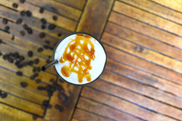 Ice caramel latte with coffee beans isolated on wooden table top view