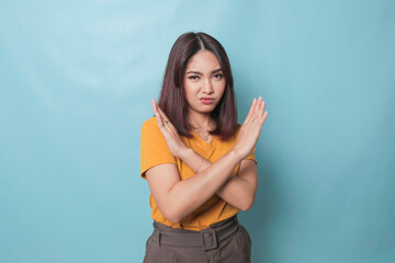 Stop. Concerned Asian woman showing refusal sign, saying no, raise awareness, standing over blue...