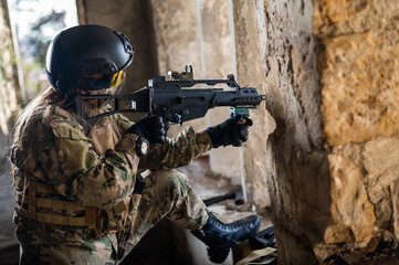 A woman in an army uniform shoots a firearm in an abandoned building. 