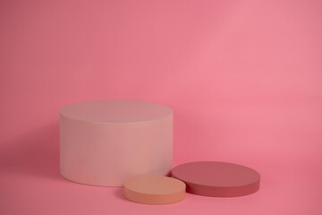 Empty podium for display cosmetic product. Platform arrangement in pink pastel color in trendy minimalist style. Composition of cylinders and cubes layout for feminine background