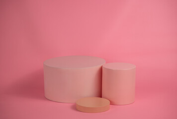 Empty podium for display cosmetic product. Platform arrangement in pink pastel color in trendy minimalist style. Composition of cylinders and cubes layout for feminine background
