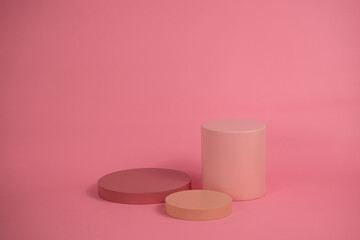 Empty podium for display cosmetic product. Platform arrangement in pink pastel color in trendy minimalist style. Composition of cylinders and cubes layout for feminine background