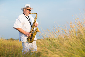 Man playing jazz on saxophone in the spring nature on a sunny day
