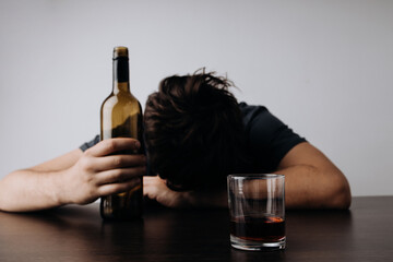 Alcoholism, addiction and treatment concept. Man with bottle and glass lying or sleeping on table