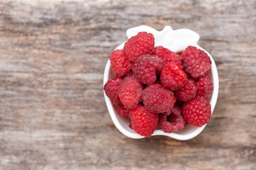 Seed ripe raspberries in a cup on a wooden background. copy space