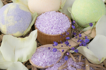 lilac bath salt, in a wooden spoon and bowl, surrounded by rose petals and bombs