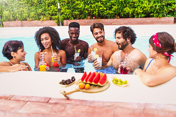 Gathering of millennials young people having fun drinking and eating healthy food and drinks inside the swimming pool - Friends having a beach party - luxury lifestyle concept