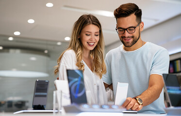 Shopping a new digital device. Happy couple buying a smartphone in store.