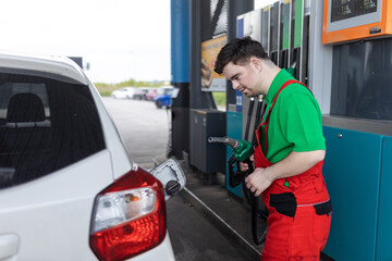 Down syndrome man employee fueling car at gas station.