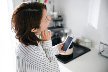 キッチンでレシピを探すお母さん © kapinon