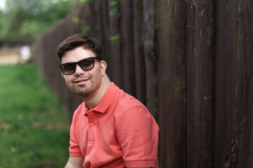 Portrait of happy young man with down syndrome standing outdoors in park and wearing sunglasses © Halfpoint