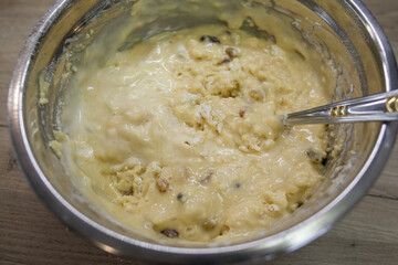 Kneading dough on a muffin or cake with raisins. Metal bowl with dough and spoon. Dough preparation for cake and bakery. Step for making muffins, pie, biscuit. Baking process step by step.