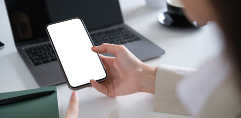 Close up view businesswoman holding smart phone with empty screen, sitting at her office desk.