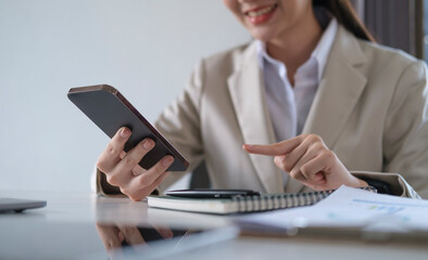 Smiling female employee checking social media, chatting on smart phone.