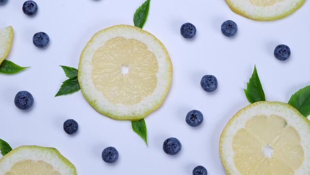 Rotation background of blueberries and lemon slices on a white background - the concept of a healthy diet. Summer bright food fruit background, food design