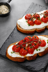 Sandwiches with ricotta cheese, cream cheese and baked tomatoes cherry on white plate. Healthy vegetarian toast with whole grain bread.
