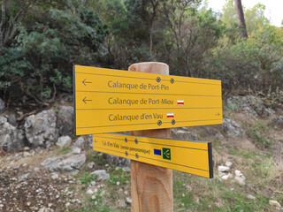 Cassis, France, October 5, 2021 - Rocky hiking path in mountain range Massif des Calanques at the French Riviera. Wooden signpost with a directional sign on a hiking trail near Calanque d'En-Vau.
