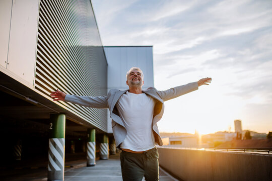 Portrait Of Happy Energetic Mature Businessman With Arms Outstretched Balancing On Wall , Feeling Free, Work Life Balance Concept.