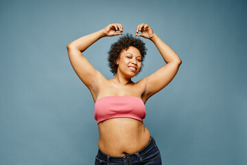 Waist up portrait of confident black woman posing against pastel blue background, copy space