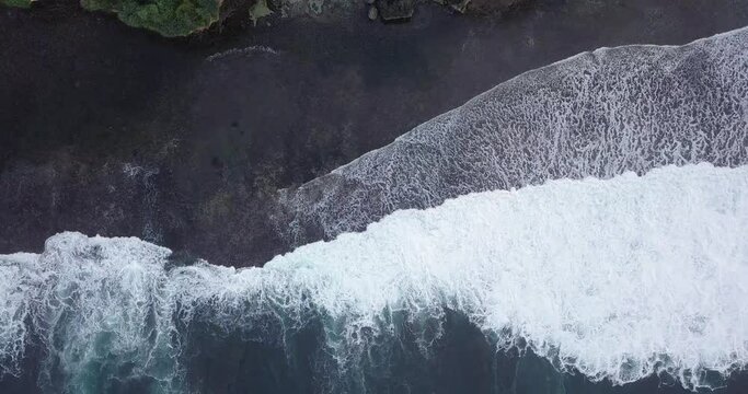 aerial drone view of cliff overgrown by tress border with the sea. shot of sea wave in Indonesia.
