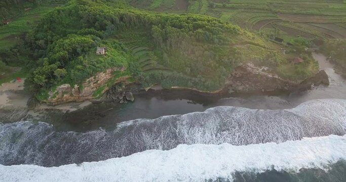 aerial drone view of cliff overgrown by tress border with the sea. shot of sea wave in Indonesia. sea ​​foam 4K video.