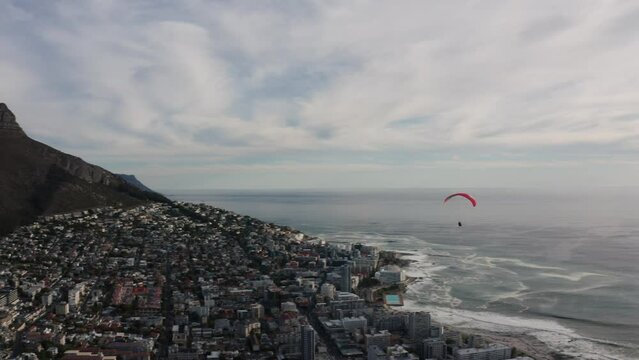 Epic paraglider flies into sunset over city of Cape Town, South Africa. Adventure and Adrenaline concept.