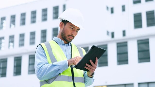 Male engineer analyzing data on digital tablet and inspecting construction site. Technician managing and project planning outdoors. Skilled worker looking or overseeing architectural operations