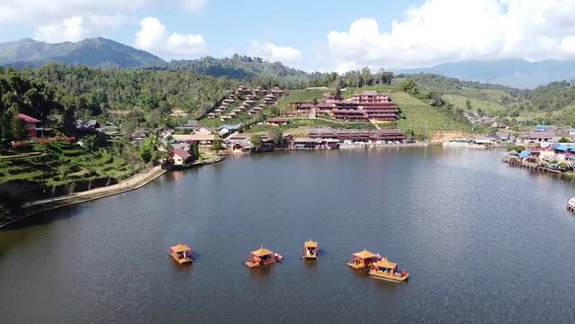 Dam in the mist Rak Thai Village Reservoir Surrounded by Chinese Yunnan style accommodation there is a raft boat with tea tables cruising in the middle of the water aerial view Mae Hong Son Thailand