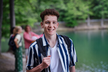 Portrait of young man with friends at background on a hiking or camping trip in the mountains in summer.