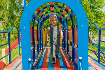 Cute funny blond little young toddler kid child boy going through the colorful arch in...