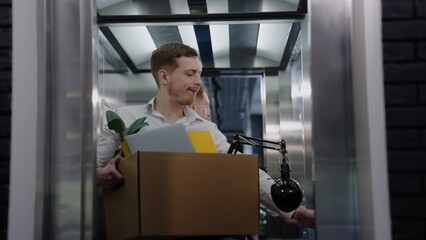 A male office employee with a box rides in the elevator on the first working day