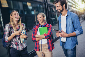 Happy university students walking after the lecture at campus.