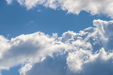 Naklejka na ściany i meble White thick and fluffy cumulus clouds in the blue sky, close up. Beautiful cloudscape