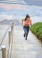 Caucasian girl climbing a staircase in a city. Training, running.
