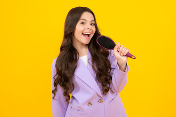 Child with long hair holding comb hairbrush for combing, beauty. Conditioner shampoo hair. Beauty kids salon. Child hairstyle. Happy face, positive and smiling emotions of teenager girl.