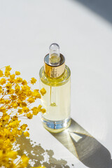 Transparent bottle with dropper pipette with serum or essential oil with beautiful yellow flowers....