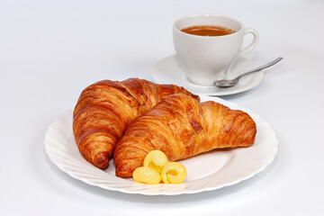 Two croissants with butter on a white plate and a cup of coffee on a white background. Croissant on white plate isolated over white background.