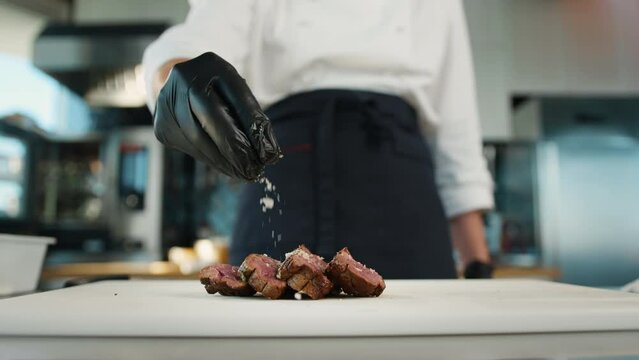 The chef sprinkles the filet mignon with coarse salt. Serving food in restaurant.