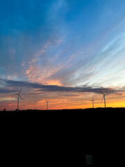Orange sunset with purple cloud in the landscape, black silhouette of the windmills