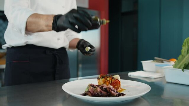 Close-up of a chef using a flavor enhancer to make filet mignon and ratatouille tastier