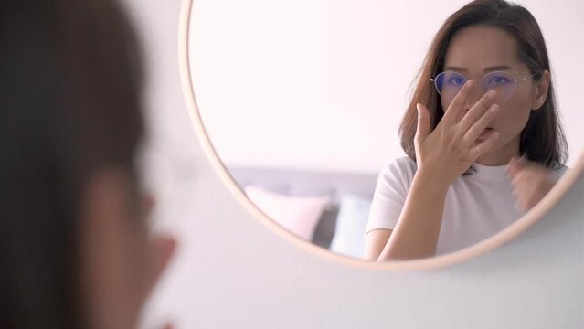 Beautiful asian woman wearing eyeglasses and looking at mirror in living room, confident and beauty concept