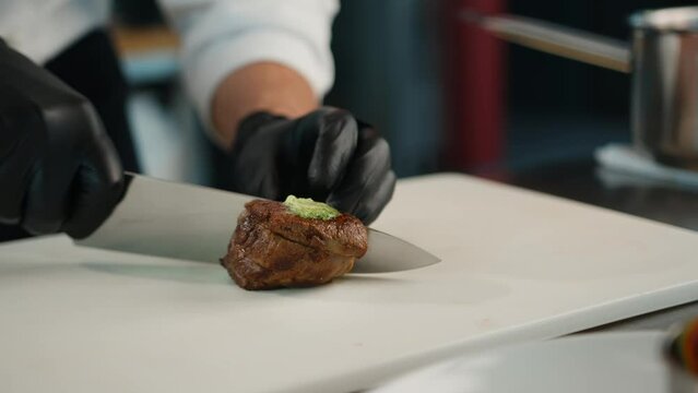 The chef cuts the filet mignon into pieces before serving the dish