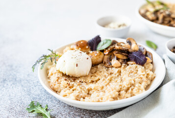 Savory porridge for breakfast. Oatmeal or spelt flakes with poached egg, fried mushrooms, herbs....