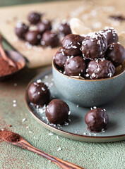 Vegan chickpea and peanut butter candies in chocolate glaze sprinkled with coconut chips. Energy balls. Healthy raw dessert without sugar.