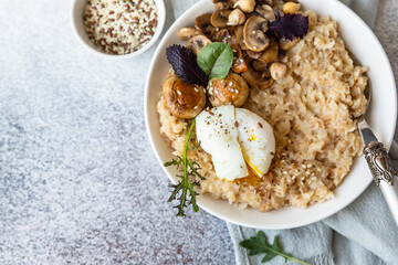 Savory porridge for breakfast. Oatmeal or spelt flakes with poached egg, fried mushrooms, herbs. Healthy food. Keto diet.