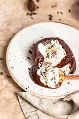 Chocolate fondant or lava cake with whipped cream, almond and chocolate pieces, brown background. Hot chocolate dessert or pudding with liquid center. Fondant au chocolate.