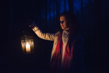 Young woman in the woods walking with lantern at night - 519318039