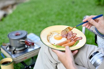 Female camper traveler eating her breakfast while enjoy camping at the campground.