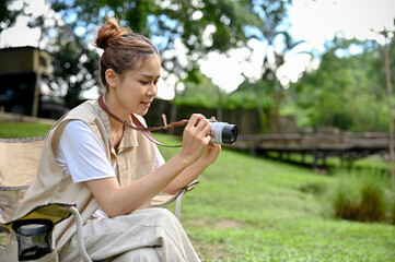 Hipster young Asian female taking a picture of the beautiful forest with her retro film camera.