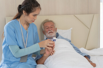 Asian nurse caregiver checking senior man oxygen with pulse oximeter. Patient resting and recovery...